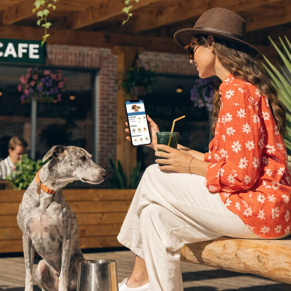 A realistic photo of a pet owner using a smartphone app to manage shared pet care routines and medication reminders during International Dog Day.