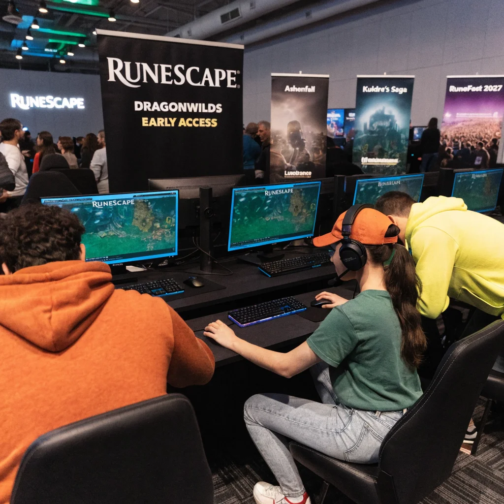 A realistic photo of a gaming convention booth showcasing RuneScape Dragonwilds early access with promotional banners featuring Ashenfall, Kuldra's Saga, Luminance, and a RuneFest 2027 crowd.