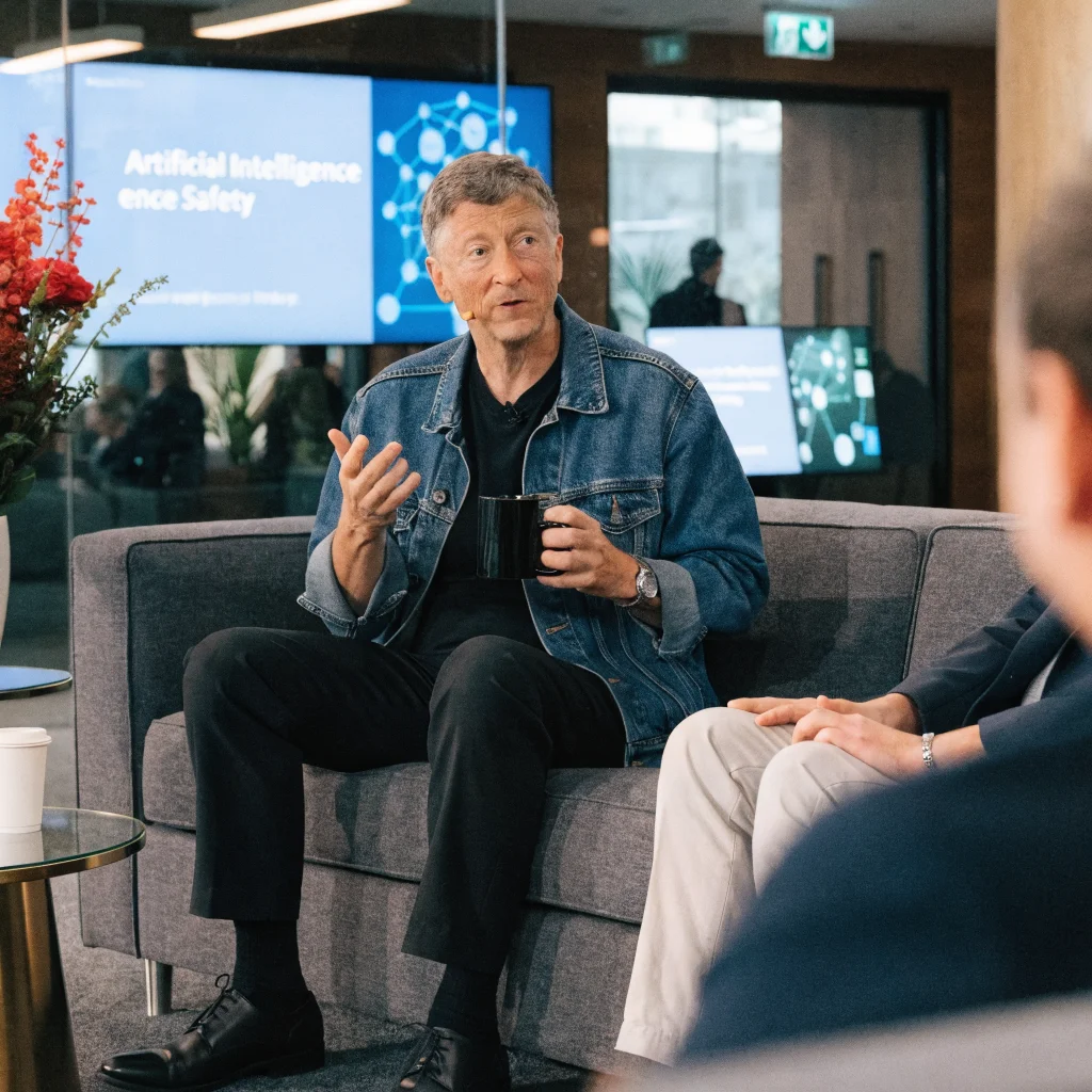 Bill Gates discussing AI safety measures and regulations to prevent AI threats, misuse, and bio-terrorism in a professional conference setting.
