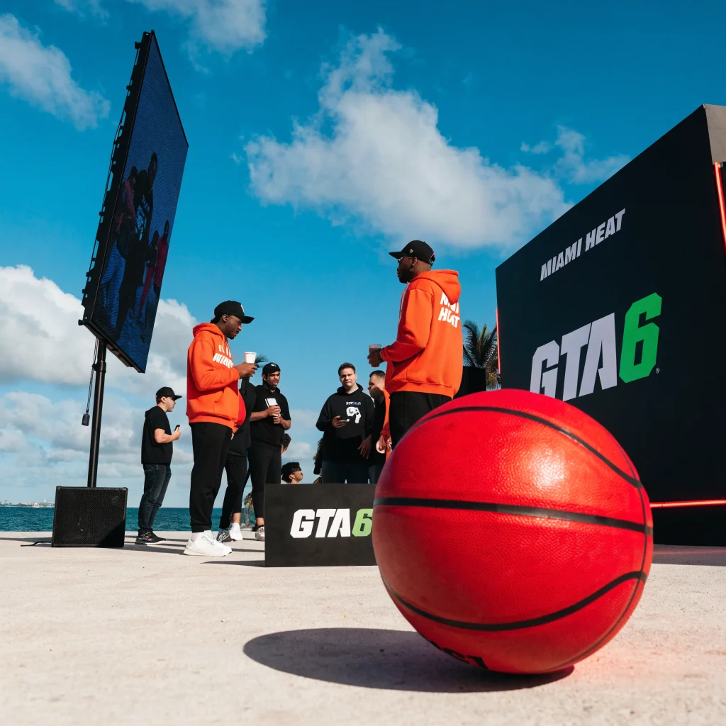 A promotional event in Miami featuring GTA 6 and Miami Heat branding with NBA players interacting with UK gaming editors and fans.