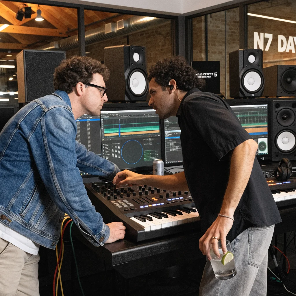 A realistic photo of composers Sam Hulick and Austin Wintory collaborating in a modern recording studio for Mass Effect 5’s soundtrack celebrating N7 Day.