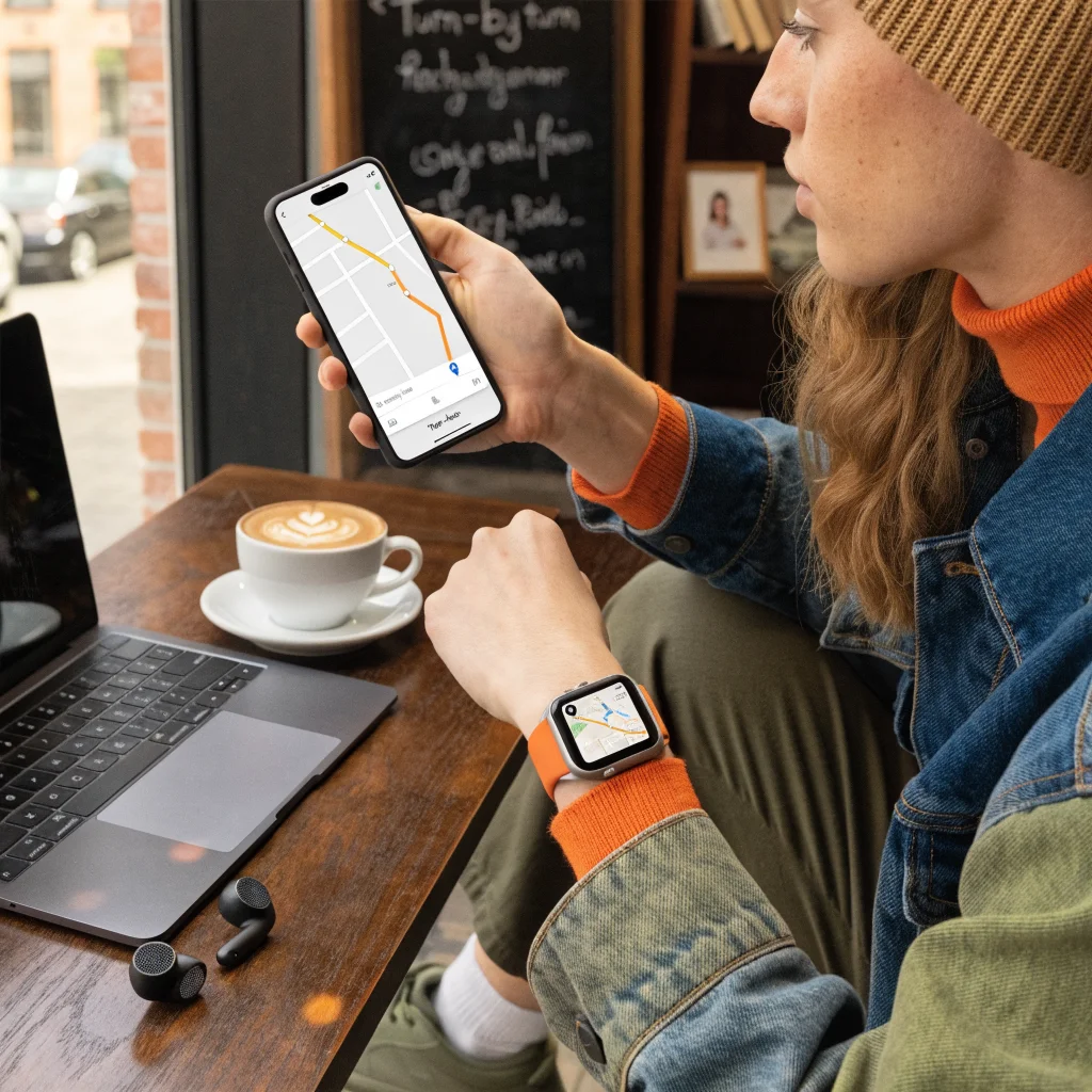 A person using Apple Maps navigation on an iPhone 17 and Apple Watch Series 12, surrounded by Apple accessories like AirPods Pro and MacBook Neo.
