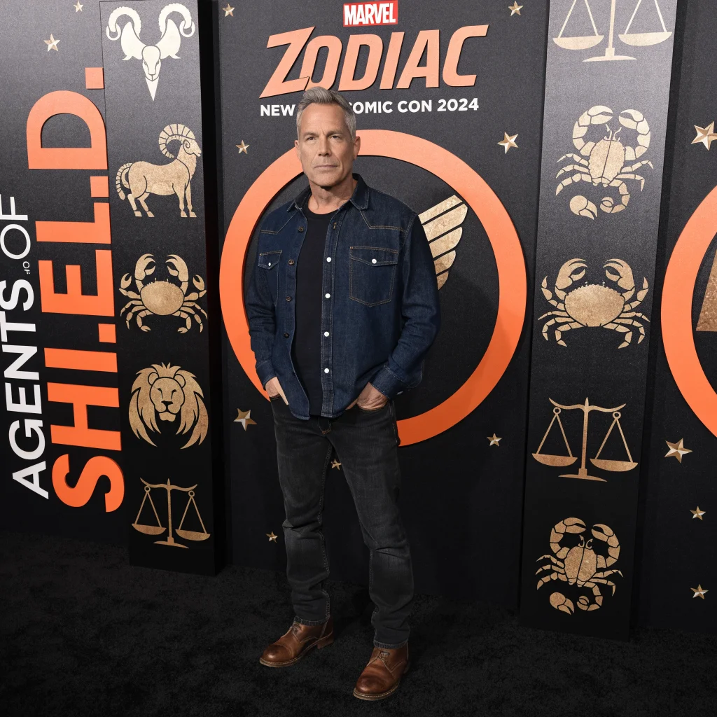 Clark Gregg as Phil Coulson stands in front of a Marvel Zodiac symbol backdrop promoting the Agents of S.H.I.E.L.D. revival at New York Comic Con 2024.